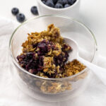A bowl of blueberry breakfast crisp with a spoon in it and a bowl of blueberries in the background. Blueberry Crisp, Easy Blueberry Crisp, Healthy Blueberry Crisp, Healthy Food, Real Food, Real Food Recipes, Healthy Food Recipes, Wholesome food, Wholesome food recipes, Whole Food, Whole Food Recipes, Realgood food, Realfooddaily Eat real, GReal Food, Goodrealfood,