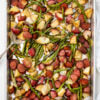 Sheet pan with Cooked sausage, potatoes, green beans, and onions, with a serving spoon. Healthy Food, Real Food, Real Food Recipes, Healthy Food Recipes, Wholesome food, Wholesome food recipes, Whole Food, Whole Food Recipes, Realgood food, Realfooddaily Eat real, Good Real Food, Goodrealfood, sheet pan meals, one pan, sheet pan, one pan meals, roasted veggies, roasted potatoes, roasted green beans, roasted onions, sheet pan sausage, sausage ring recipes, one pan sausage, sheet pan sausage, sheet pan meals, easy meals, under 30, dinner ideas, main course