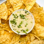 A bowl of queso dip on a plate filled with tortilla chips. Healthy Food, Real Food, Real Food Recipes, Healthy Food Recipes, Wholesome food, Wholesome food recipes, Whole Food, Whole Food Recipes, Realgood food, Realfooddaily Eat real, Good Real Food, Goodrealfood, cheese sauce, cheese dip, queso cheese, queso dip, spicy cheese dip, spicy dip, chip dip, hot dip, appetizer, cheese sauce