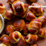 Pretzel pigs in a blanket with a bowl of cheese sauce.