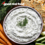 A bowl of dill dip with veggies and crackers.