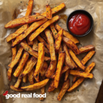 sweet potato french fries on parchment with a small bowl of ketchup.