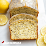 a lemon poppy seed loaf sliced on the counter with fresh lemons.