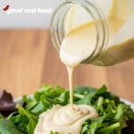 Caesar dressing being poured over a salad.