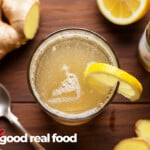 A glass of Ginger Ale surrounded by lemons and ginger.