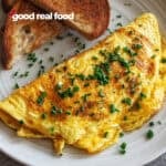 An egg and cheese omelette on a plate with toast.