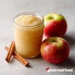 Easy homemade Applesauce in a mason jar with apples and cinnamon sticks.