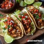 Chicken tacos, garnished with fresh pico, cheese, and limes.