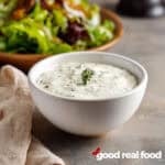 A bowl of homemade blue cheese dressing next to a side salad.