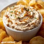 French Onion Dip in a white bowl surrounded by potato chips.