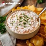 A bowl of boat dip surrounded by potato chip.