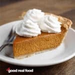 A slice of pumpkin pie, topped with whipped cream.