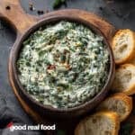 Spinach Dip in a wooden bowl with bread for dipping.