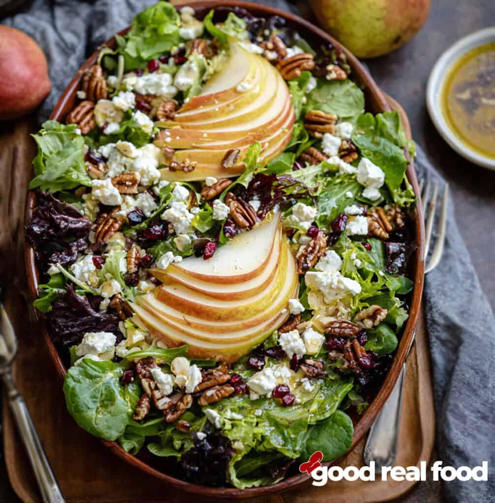 A pear salad on a wooden platter.