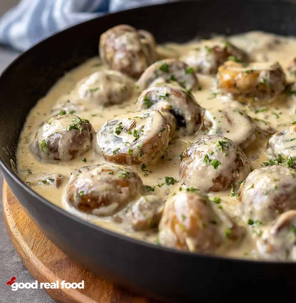 A pan of creamy garlic parmesan mushrooms, viewed from the side.