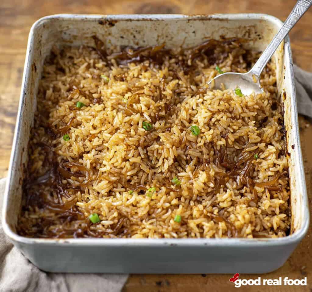 a pan of stick of butter rice with a serving spoon in the dish.