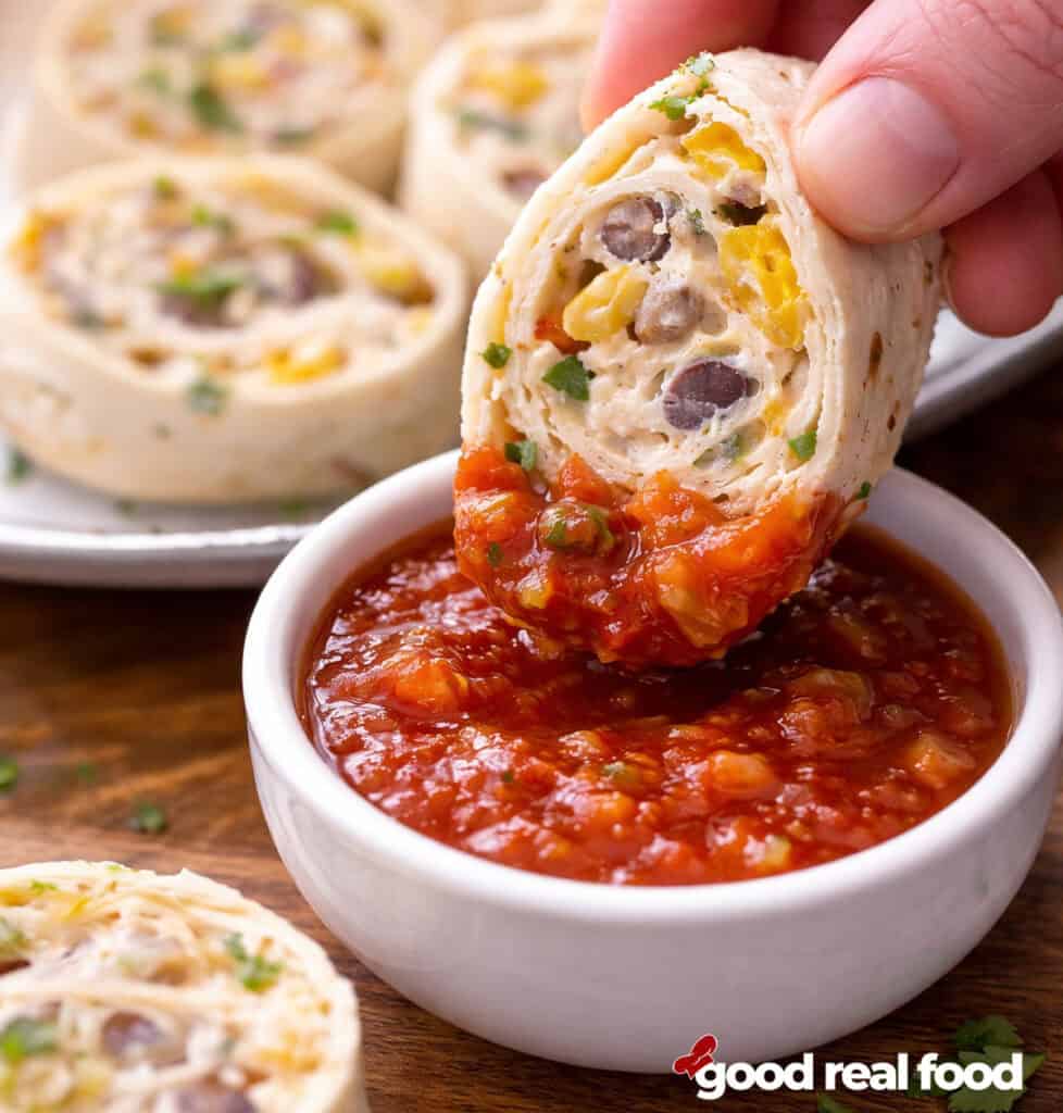 A fiesta pinwheel being dipped in salsa.