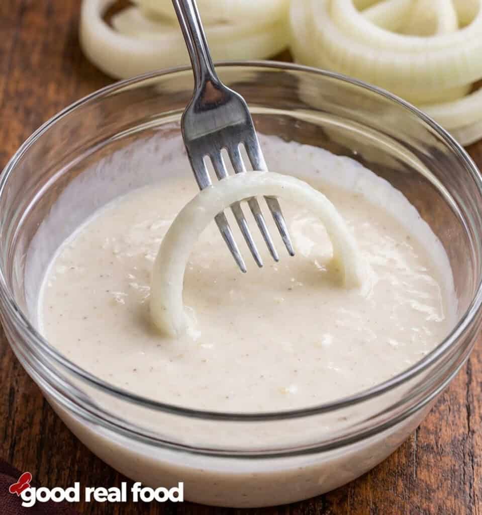Dipping and onion into the onion ring batter.