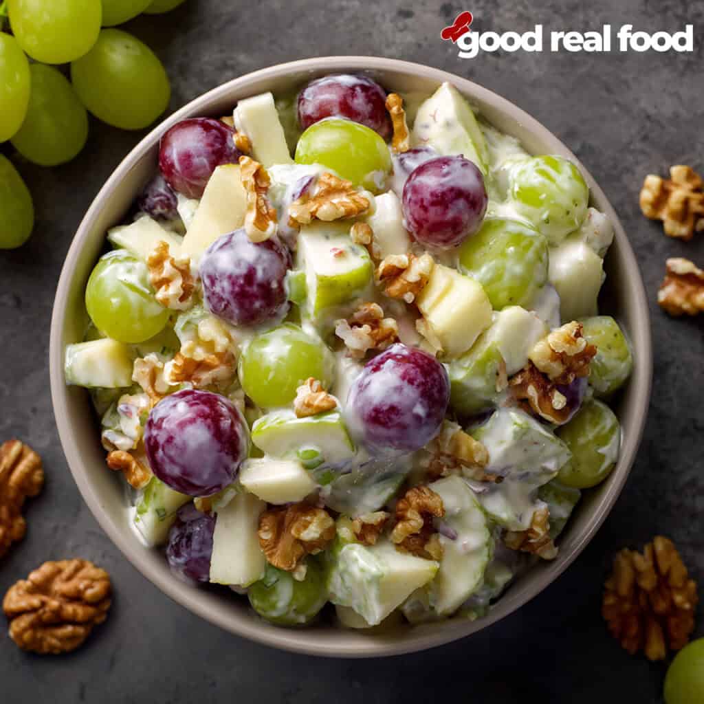 A bowl of creamy Waldorf salad with grapes, apples, and walnuts.