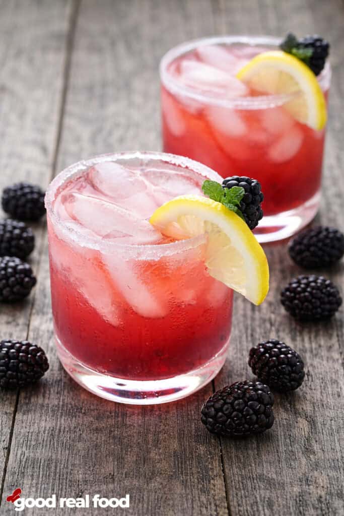Blackberry Moscato Spritzer in a clear glass garnished with lemons and blackberries.