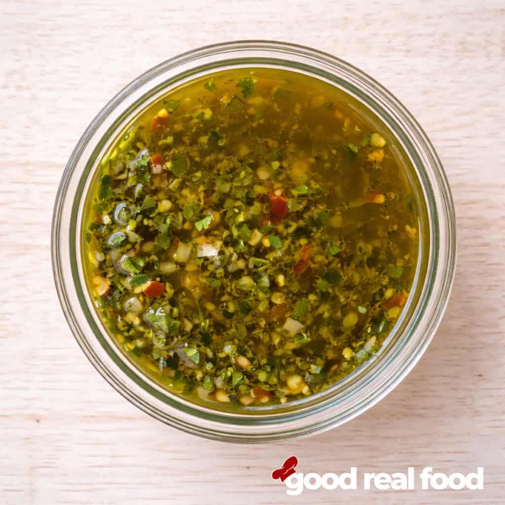 A glass bowl of chimichurri sauce.