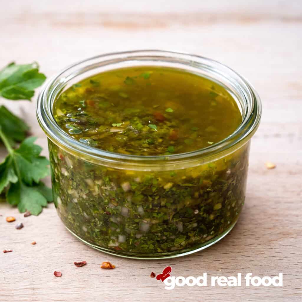 A glass bowl of chimichurri sauce.