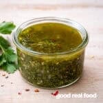A glass bowl of chimichurri sauce.