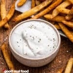 A bowl of garlic sauce with french fries.