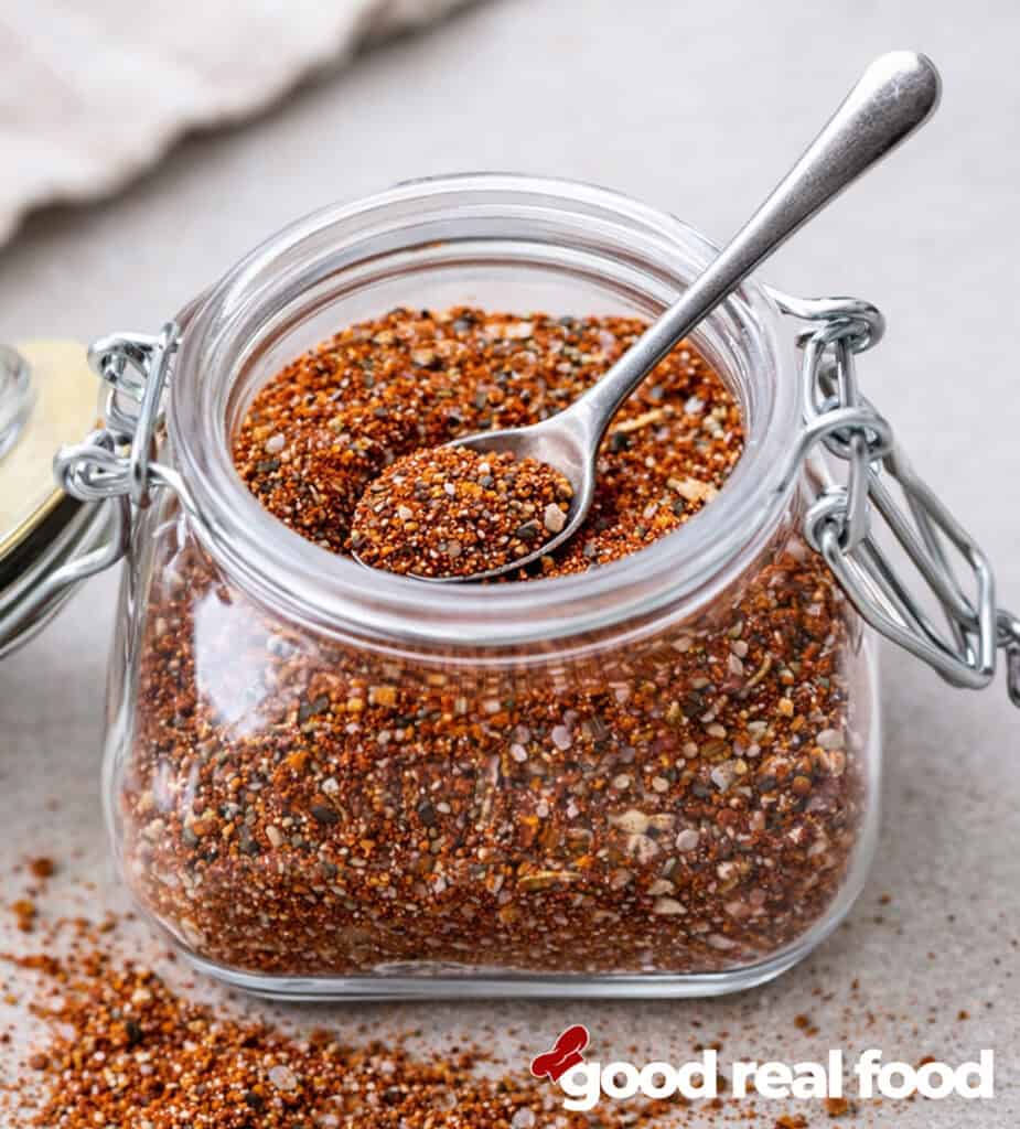 A jar of homemade hamburger seasoning with a spoon.