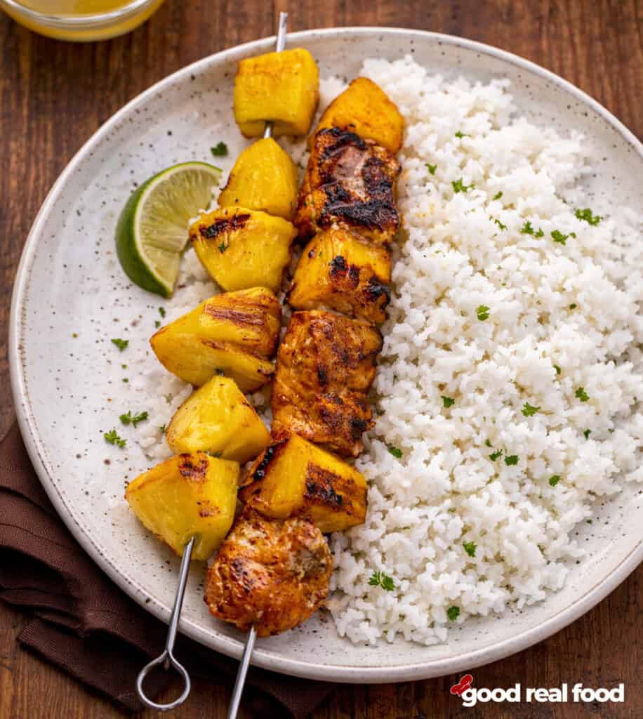 Pineapple and salmon skewers on a plate with rice.