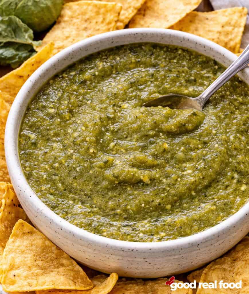 A bowl of salsa verde with tortilla chips.