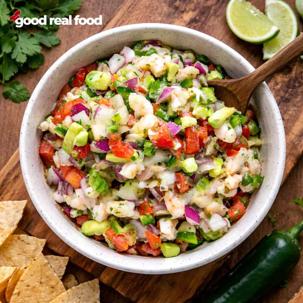 A bowl of Shrimp Ceviche with limes and tortilla chips.