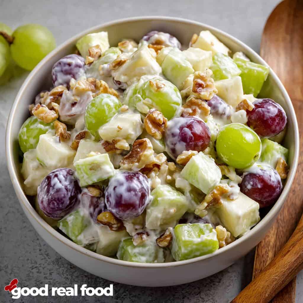 A bowl of creamy Waldorf salad with grapes, apples, and walnuts.