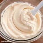 Ermine Frosting in a clear bowl with a spatula.