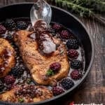 a skillet with blackberry pork chops
