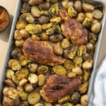 A sheet pan of with blackened chicken and potatoes on a wood table