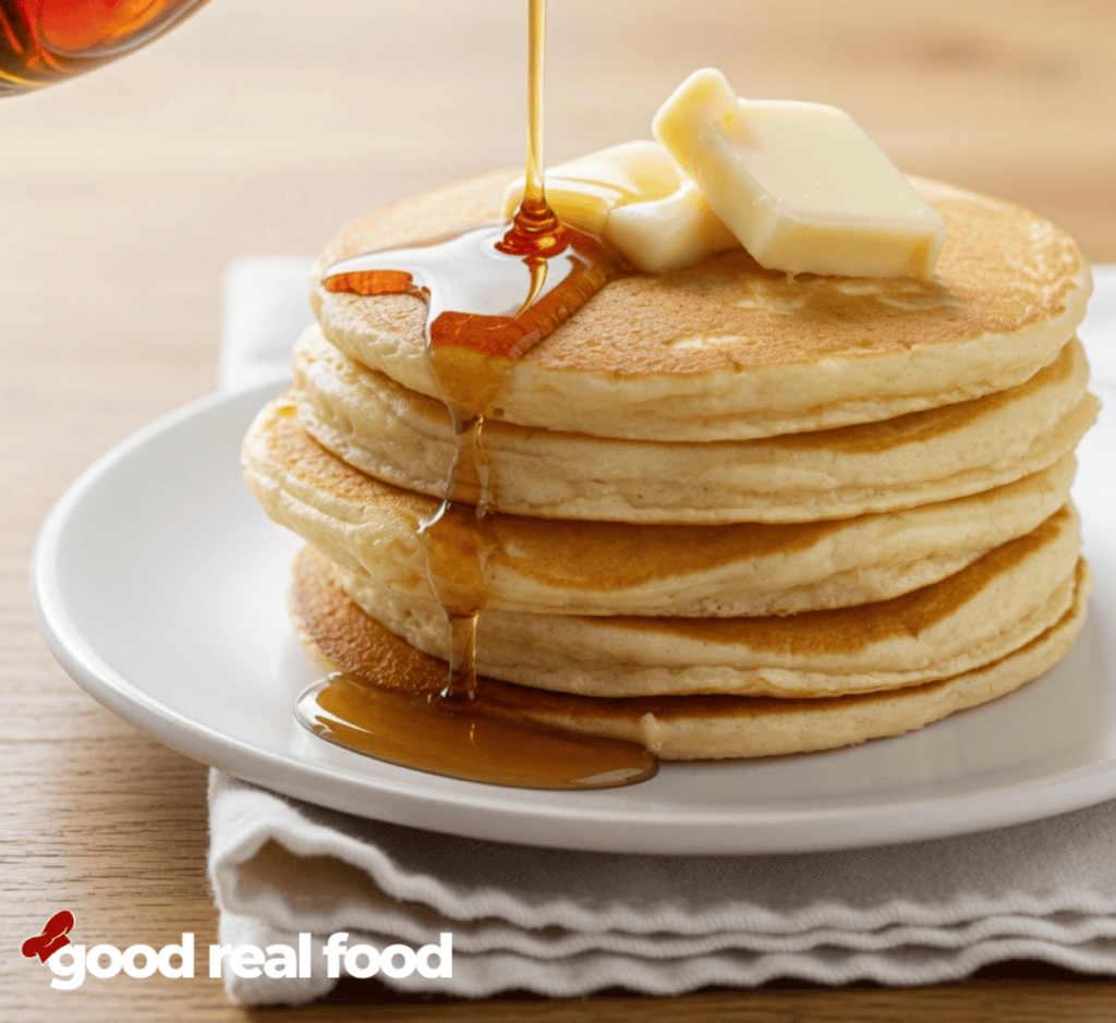 syrup over a stack of Fluffy Buttermilk Pancakes Drizzling syrup over a stack of Fluffy Buttermilk Pancakes with butter on it.