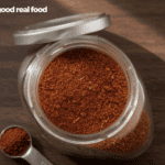 A jar of taco seasoning from above sitting on a dark wood counter