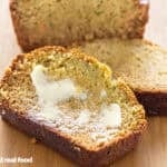 Sliced zucchini bread with butter on a wood counter