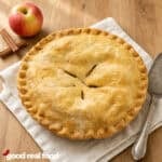 Classic apple pie on a cloth napkin with a metal server on a wood counter