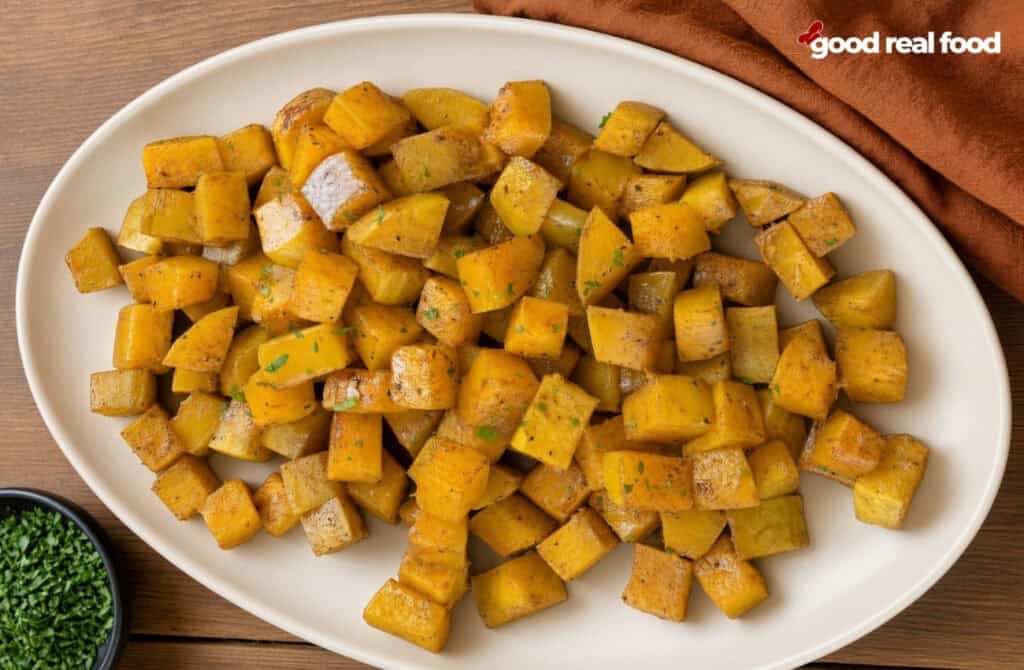 Maple Cinnamon Roasted Squash on a white plate on a wood counter Maple Cinnamon Roasted Squash on a white plate on a wood counter next to a bowl of garnish and a cloth napkin