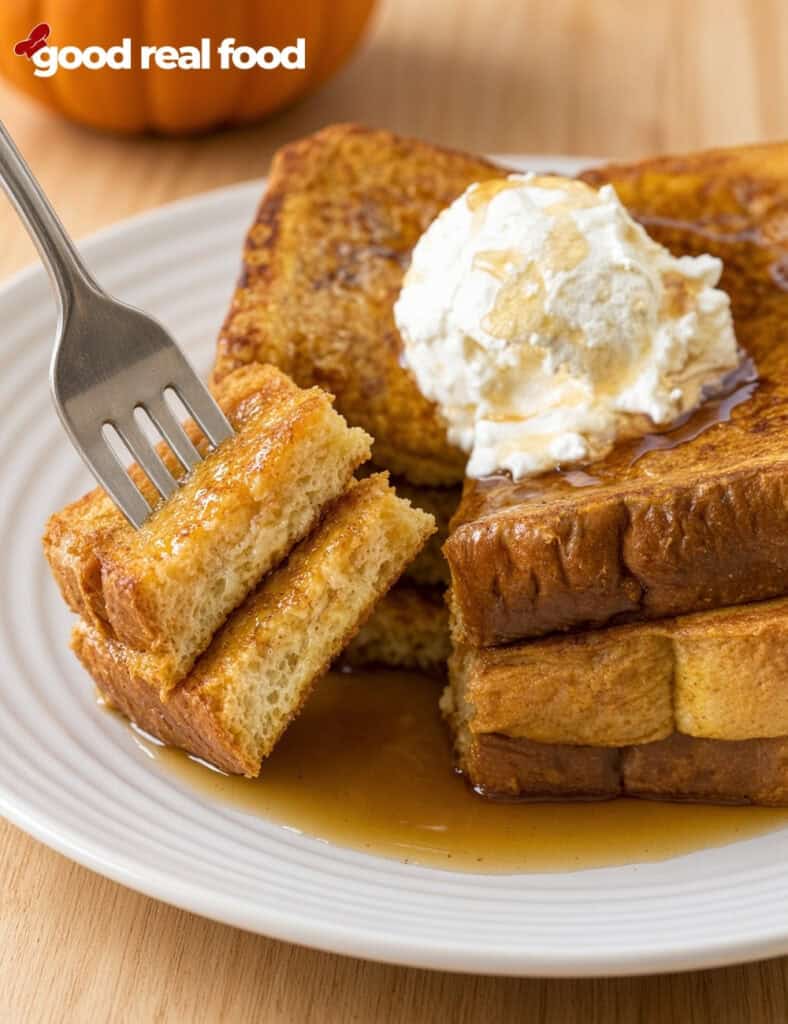 a plate with a stack of pumpkin spice French toast with a piece on a fork a plate with a stack of pumpkin spice French toast with a piece on a fork on a white plate on a wood counter next to a pumpkin