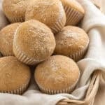 a basket of spiced apple cider muffins in a cloth napkin on a wood counter
